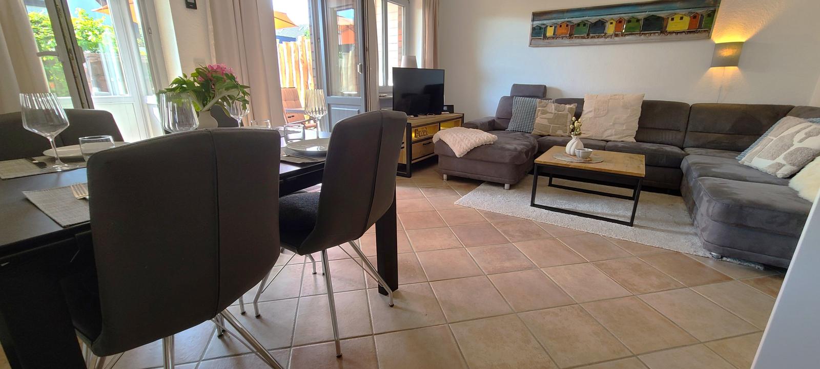 Wohn- und Essbereich mit Sofa, Esstisch und Terrassentür.