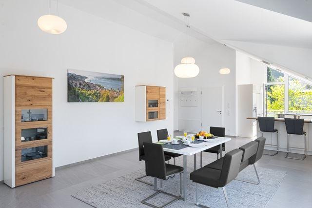 Esszimmer mit Tisch, Stühlen und Küchenbereich. Wandbild und Holzschränke sind sichtbar.