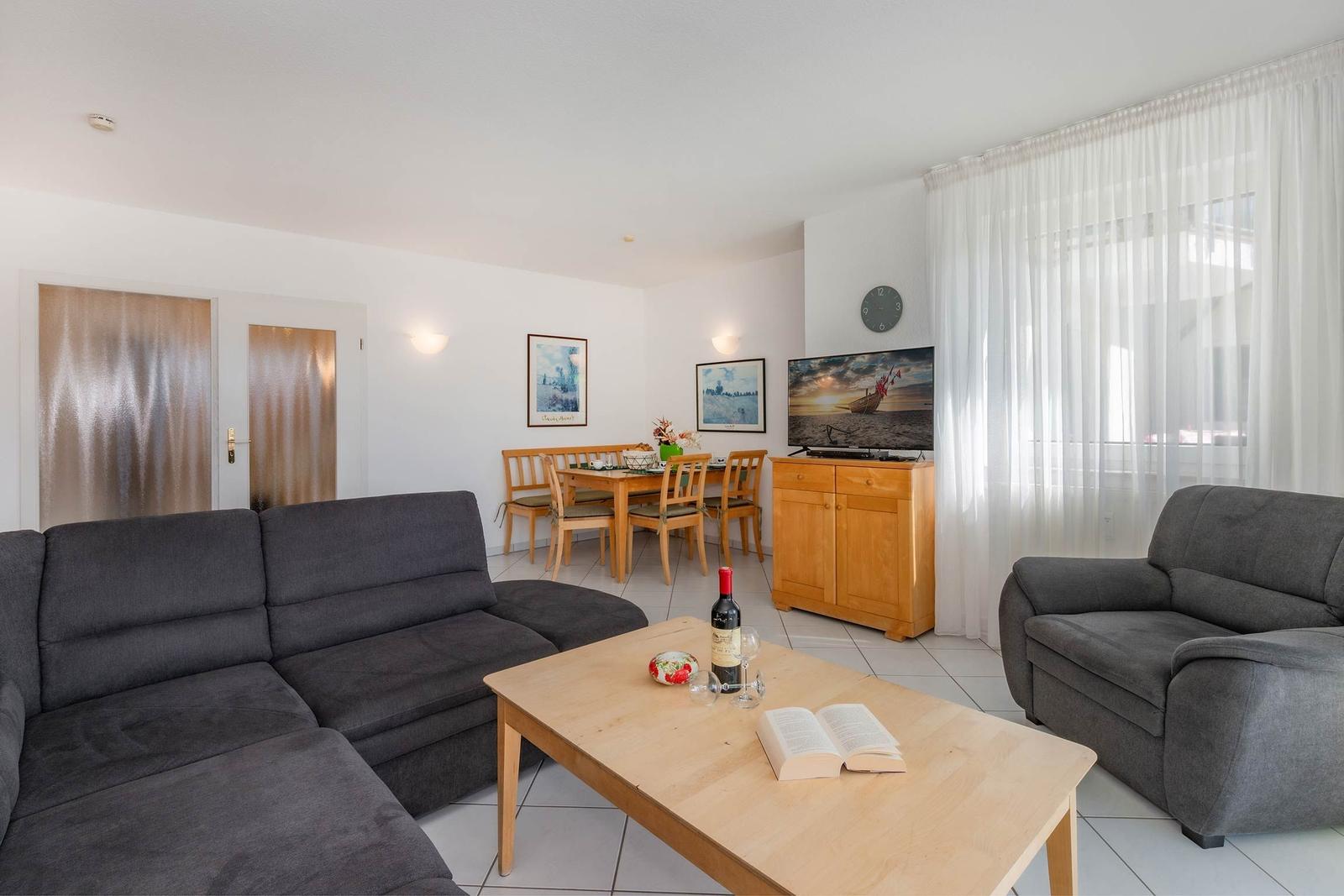 Wohn- und Essbereich mit Sofa, Couch, Tisch und Fernseher.