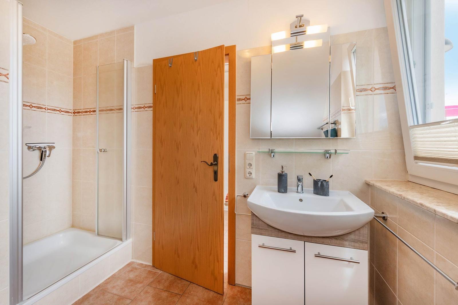 Badezimmer mit Dusche, Waschbecken und Spiegel