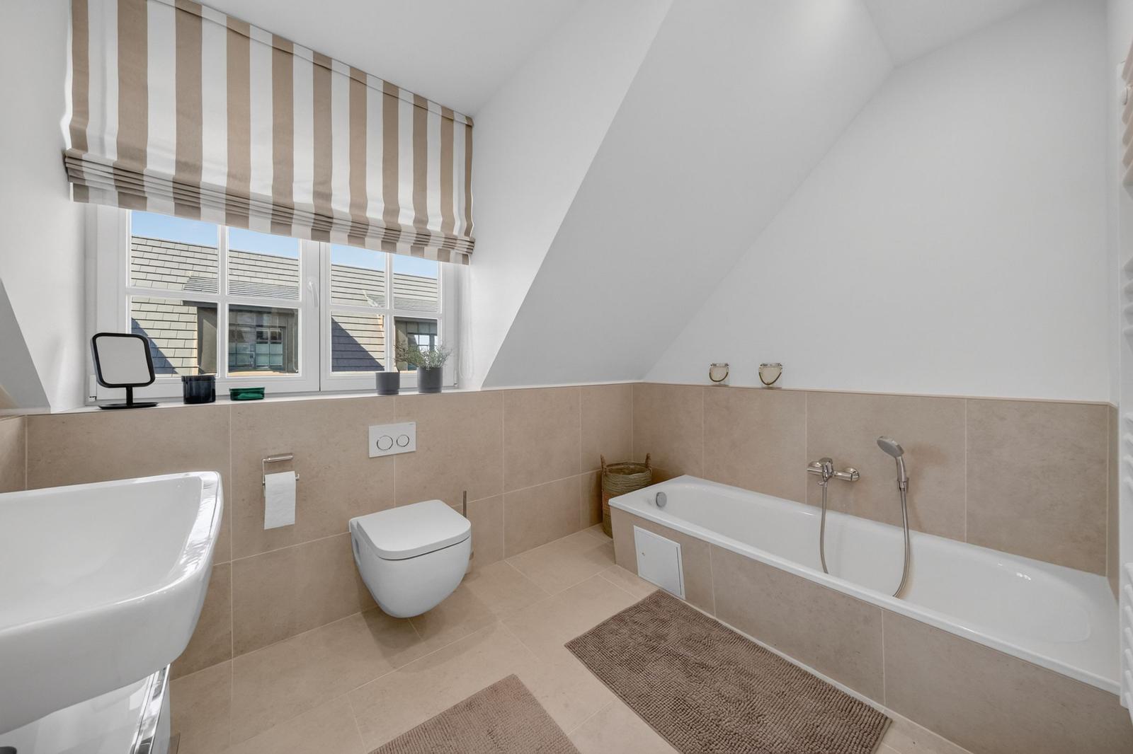 Badezimmer mit Badewanne, Toilette und Waschbecken unter einem Dach