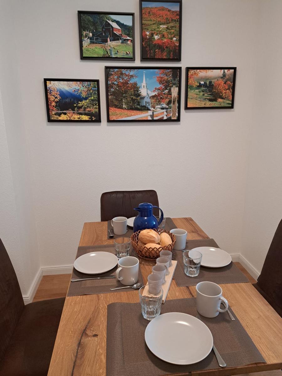 Esszimmer mit Holztisch, Stühlen und Wandbildern