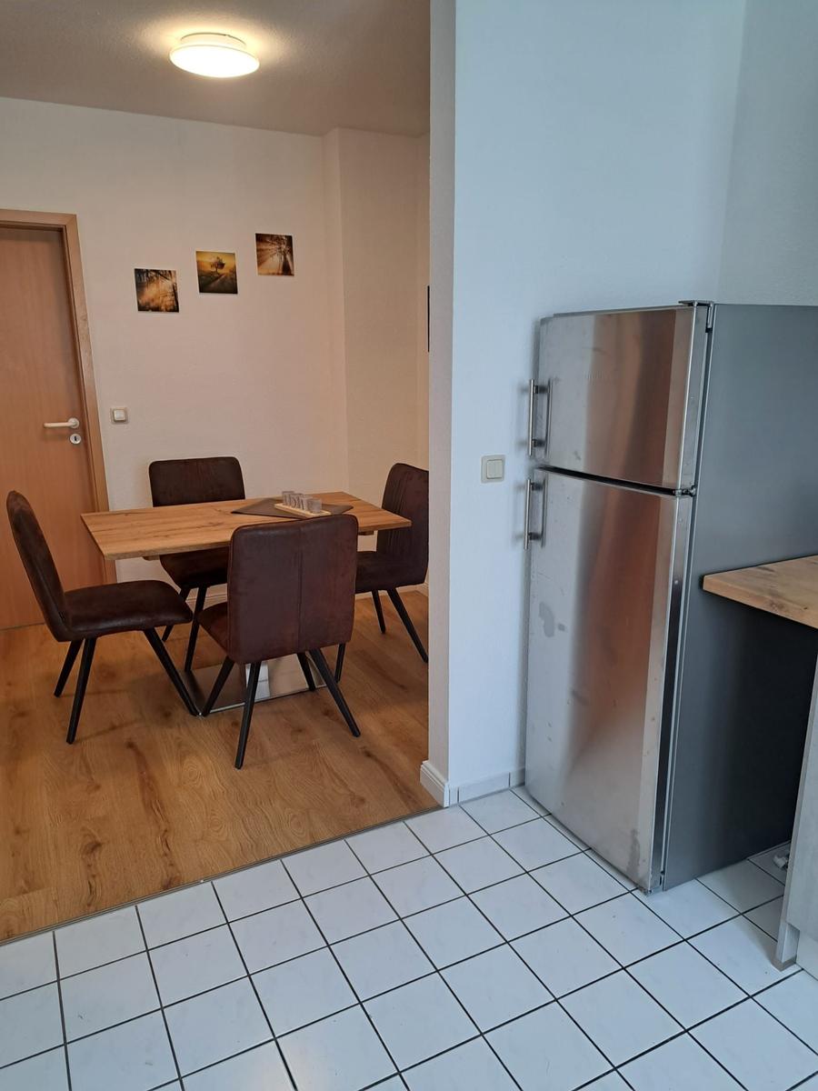 Küche mit Kühlschrank und Essbereich mit Tisch und Stühlen.