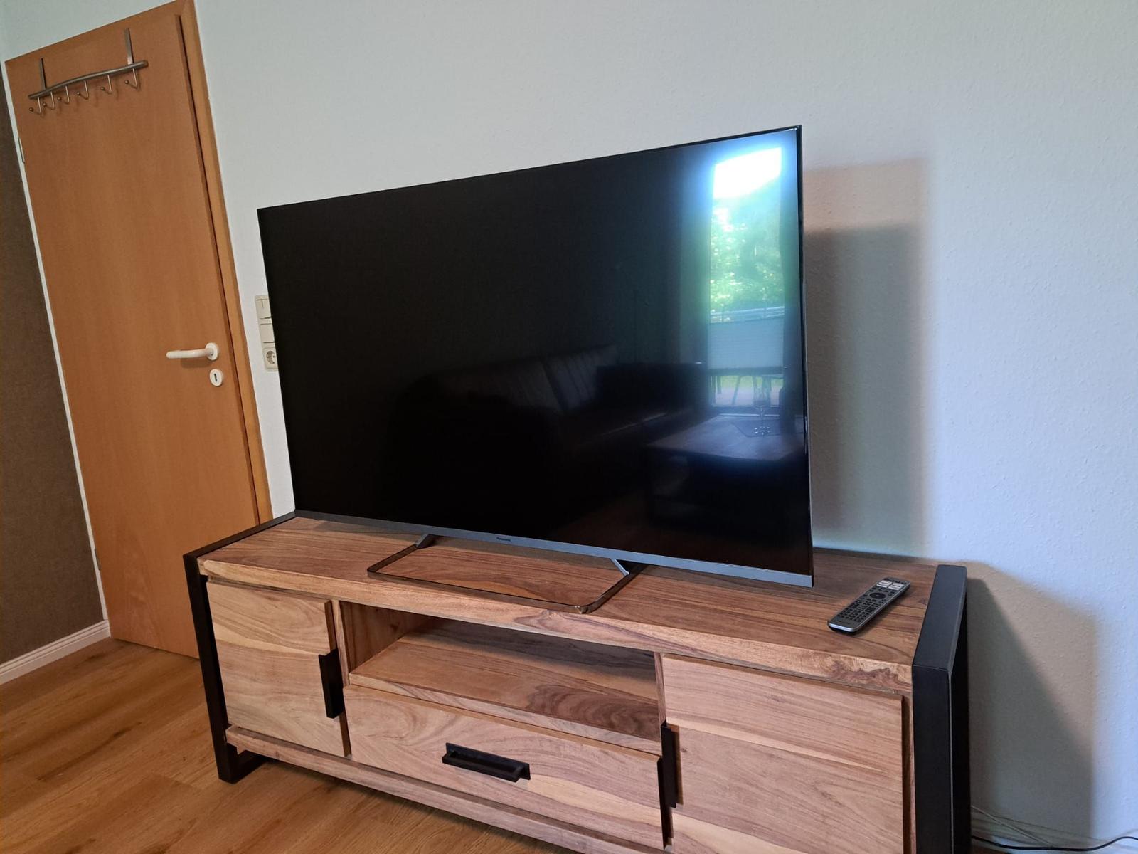 Flachbildfernseher auf Holz-TV-Schrank mit Fernbedienung
