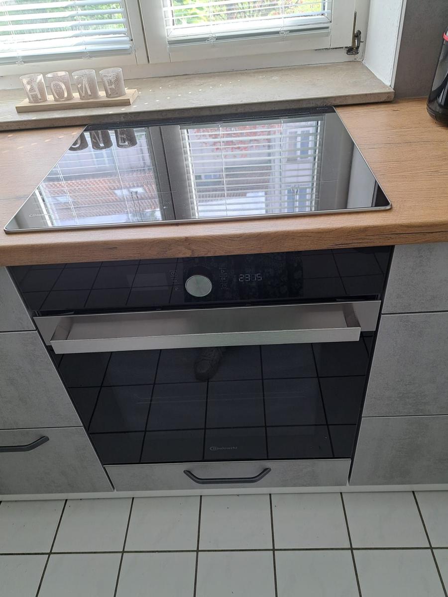 Küchenzeile mit integriertem Herd und Backofen unter Holzoberfläche.