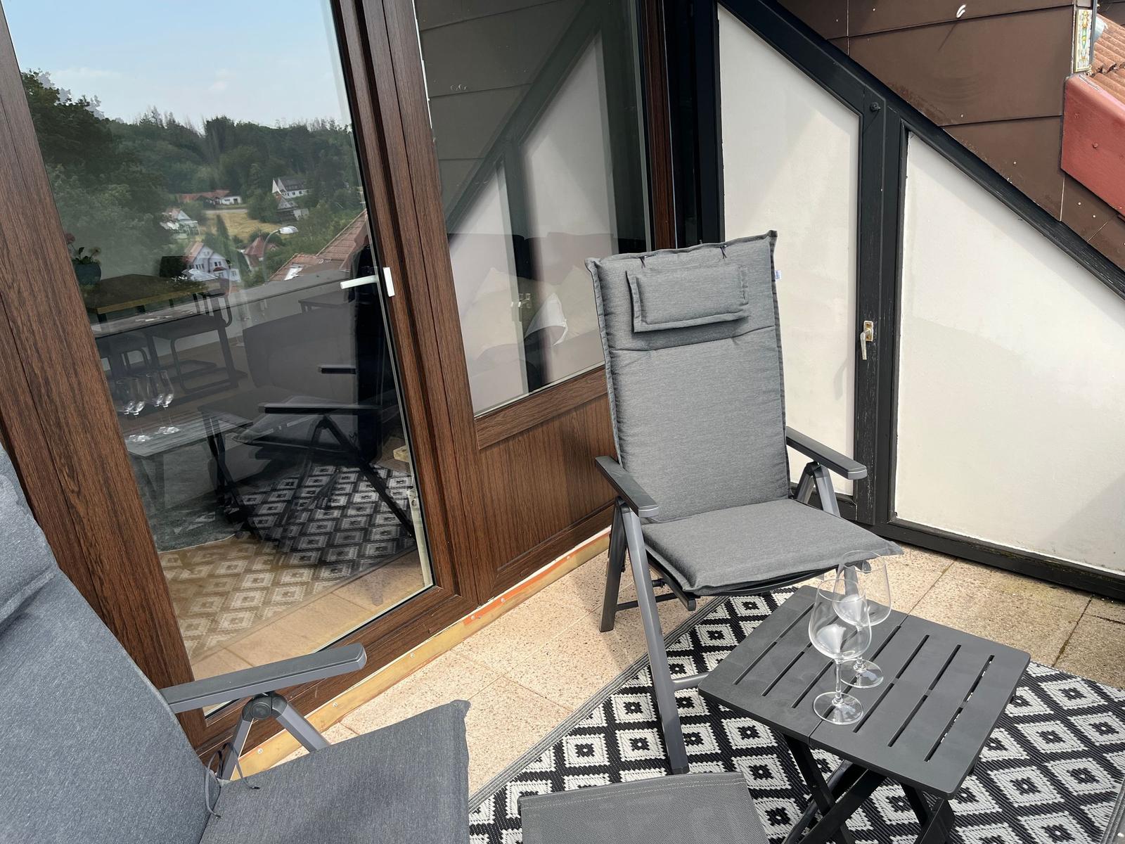 Terrasse mit Sitzgelegenheit und Tisch. Blick auf grüne Landschaft.