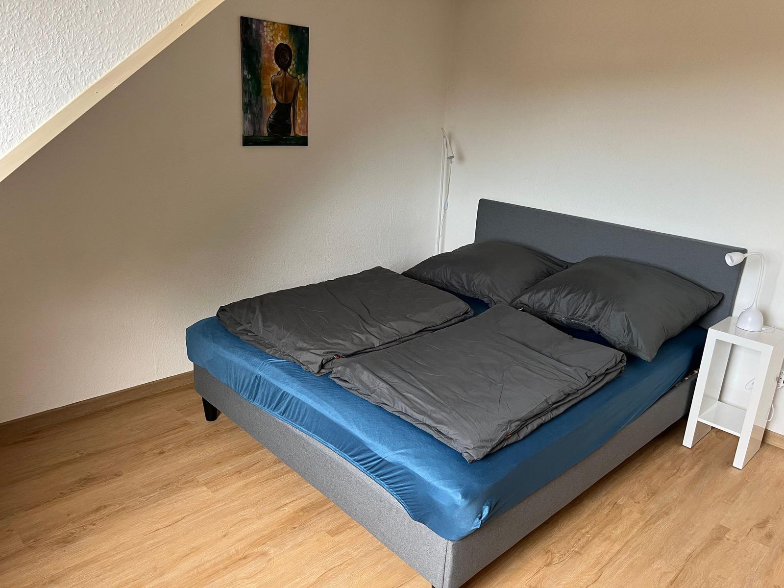 Schlafzimmer mit Doppelbett, Holzboden und Wandbild.