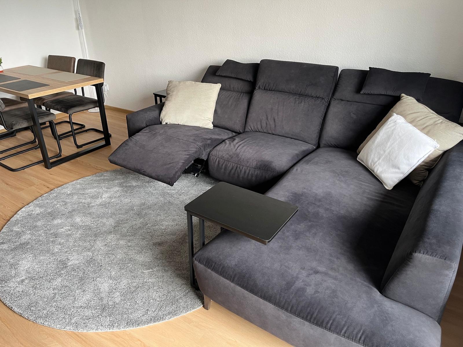 Ein großes graues Sofa mit Kissen und einem runden Teppich im Wohnzimmer.