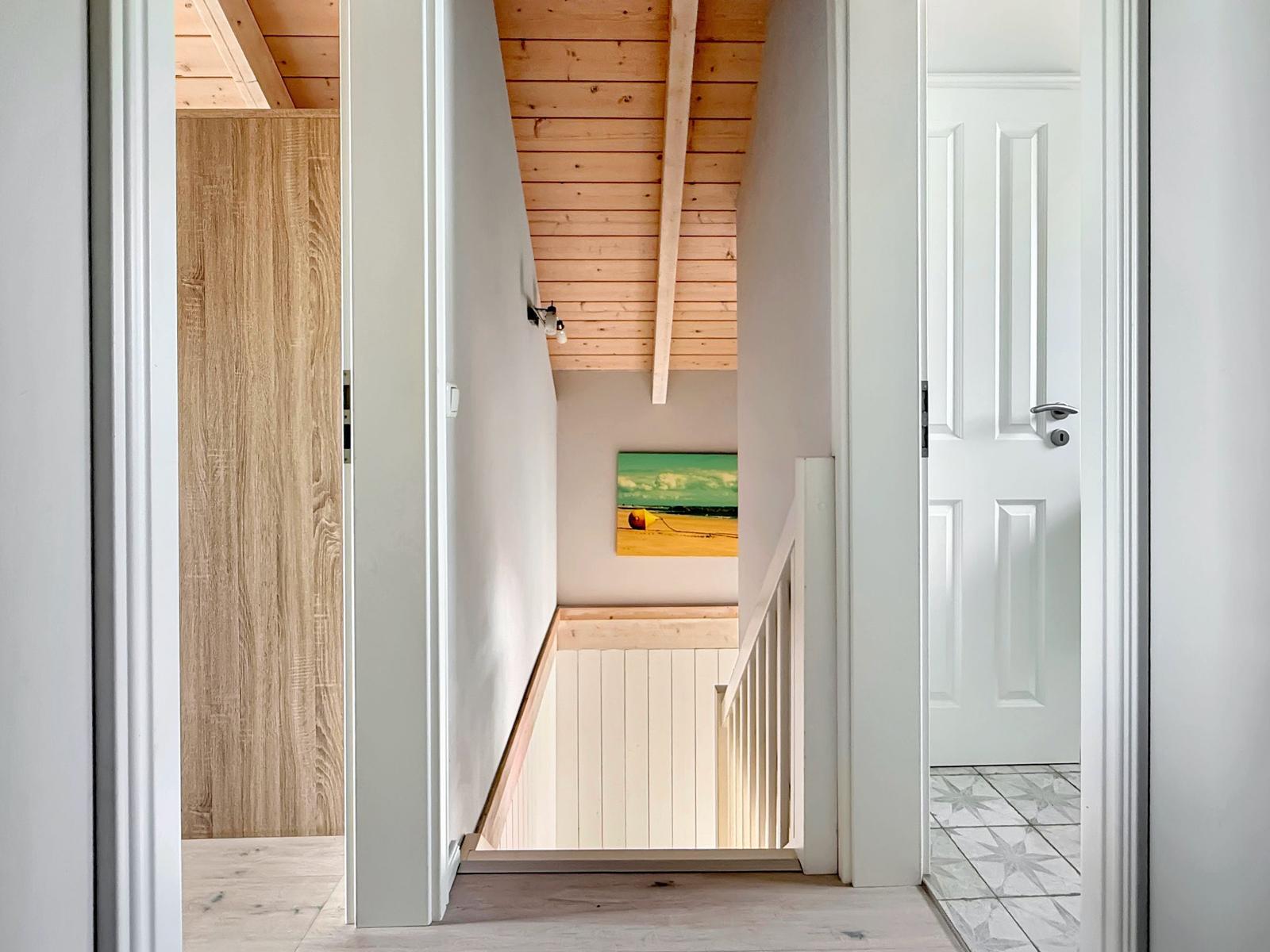 Hausflur mit Holzdecke, Treppe und Wandbild.