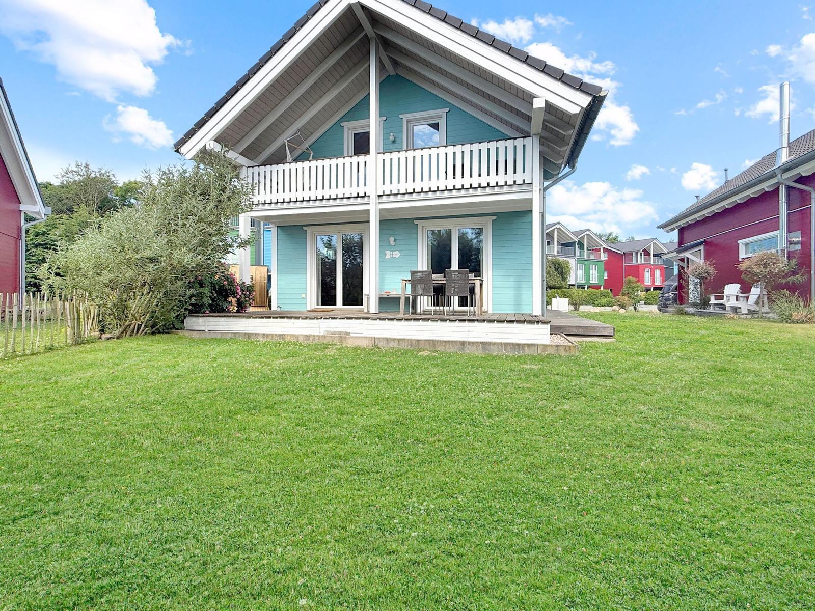 Ein hellblauer Ferienhaus mit Balkon und Terrasse im Garten.