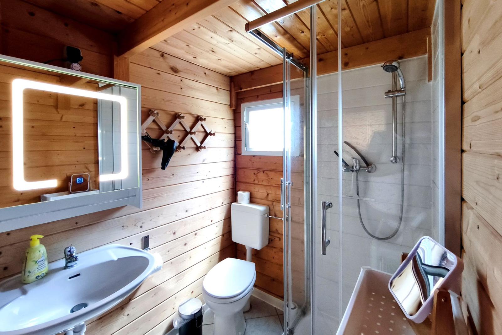 Modernes Badezimmer mit Glasedelstahl-Dusche und beleuchtetem Spiegel