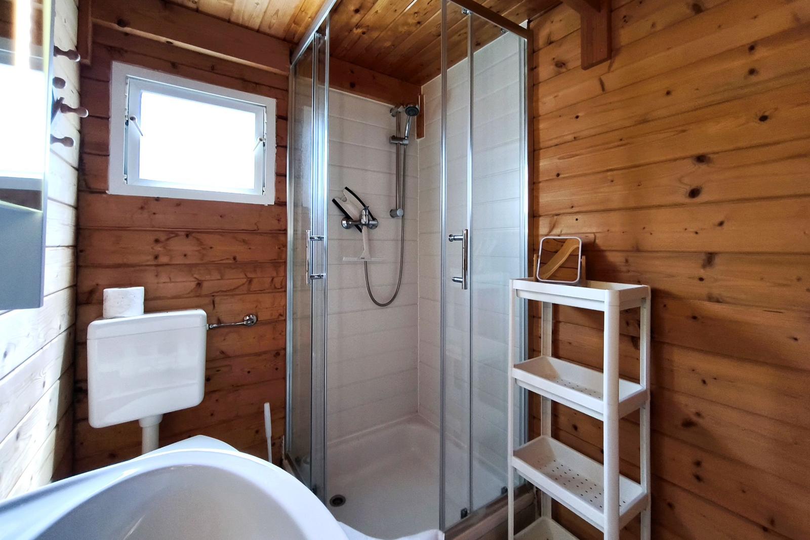 Detailansicht des Badezimmers mit Dusche, Waschbecken und praktischen Ablagen