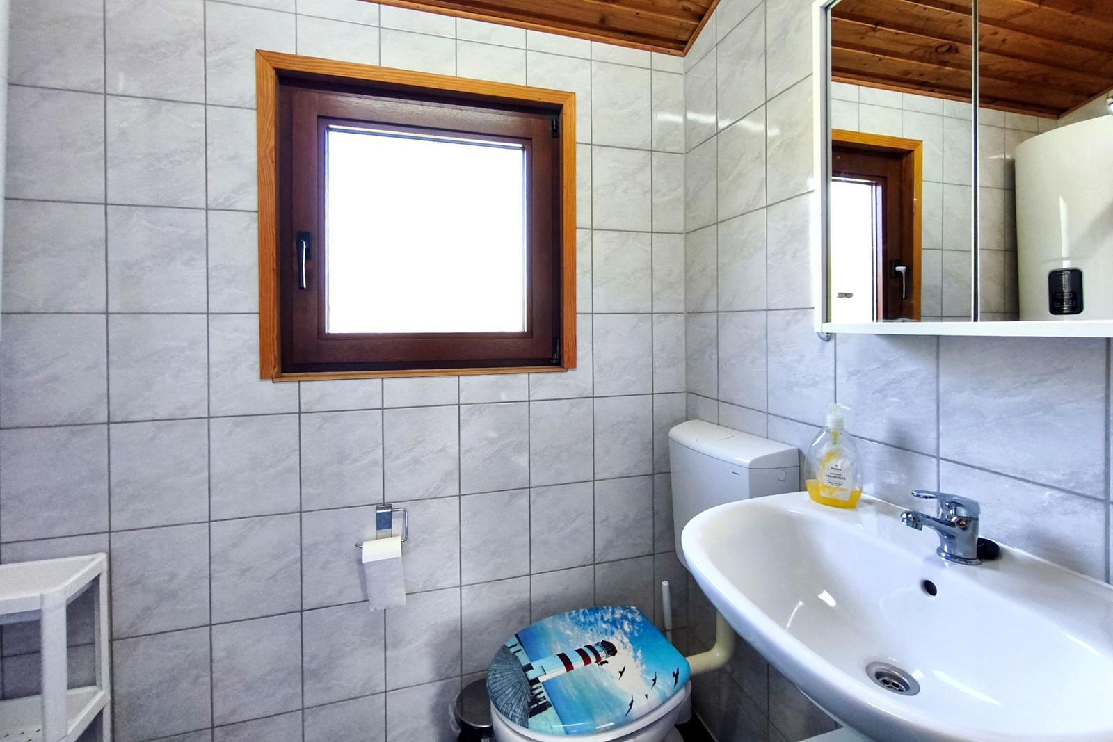 Badezimmer mit Toilette, Waschbecken und Fenster