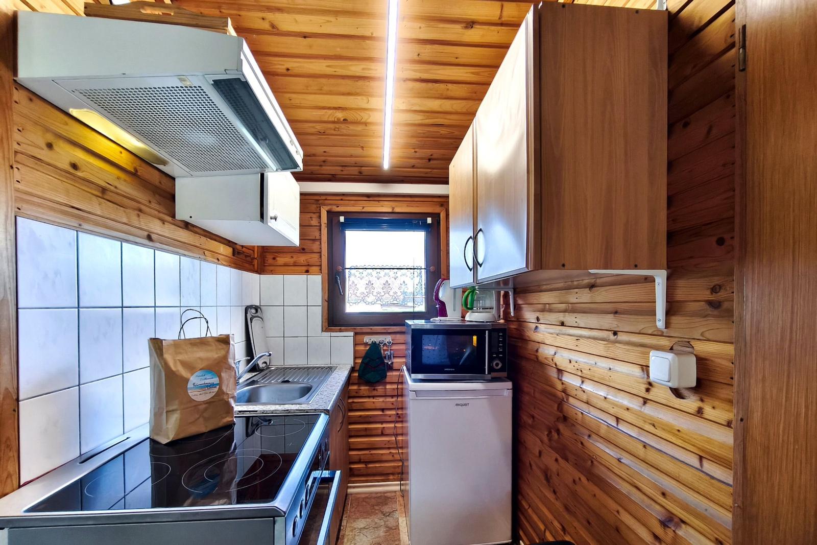 Küche mit Holzwand, Spüle, Herd, Kühlschrank und Mikrowelle.