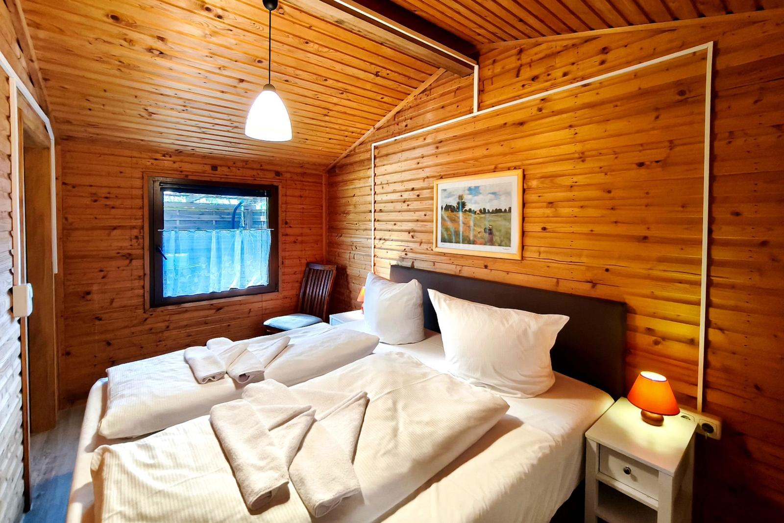 Schlafzimmer mit Holzwand, Bett, Nachttisch und Fenster.