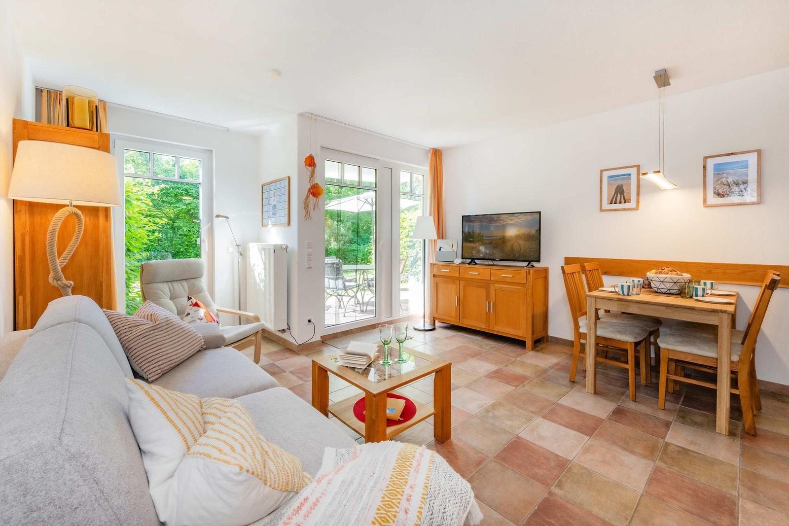 Wohn- und Essbereich mit Sofa, TV und Terrassentür.