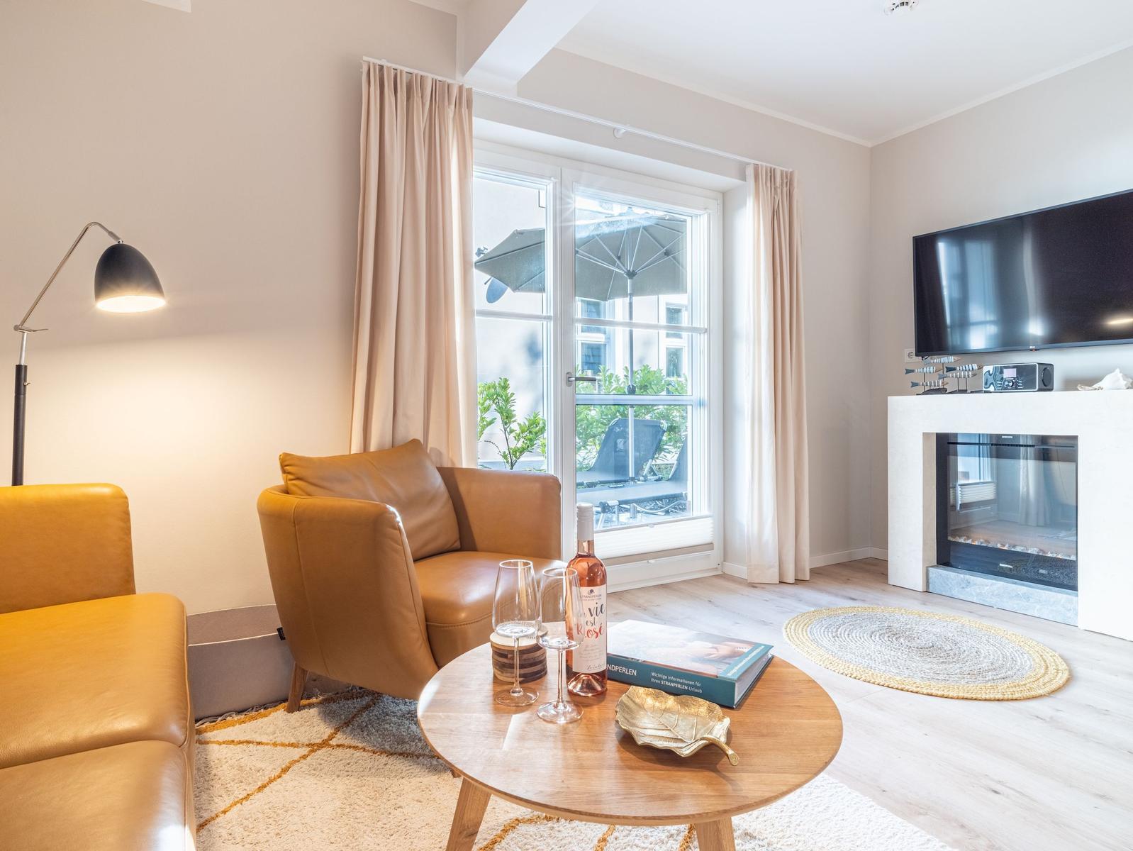 Wohnzimmer mit Ledersofa, TV und Kamin. Durchgangsfenster mit Blick auf Balkon.