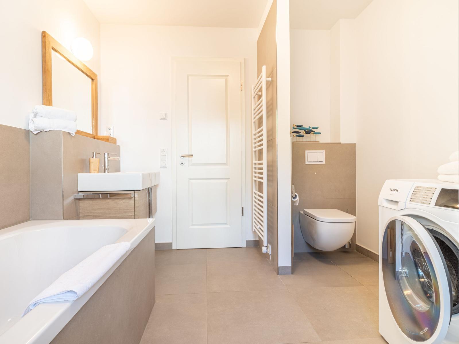 Badezimmer mit Badewanne, Waschmaschine und WC