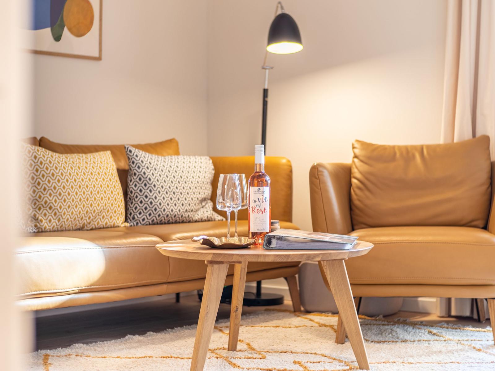 Ein Wohnzimmer mit braunem Sofa, Tisch und Weinflasche.