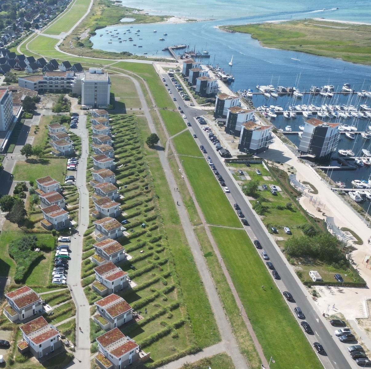 Luftbild von Wohnhäusern, Straßen und einem Hafen mit Booten.