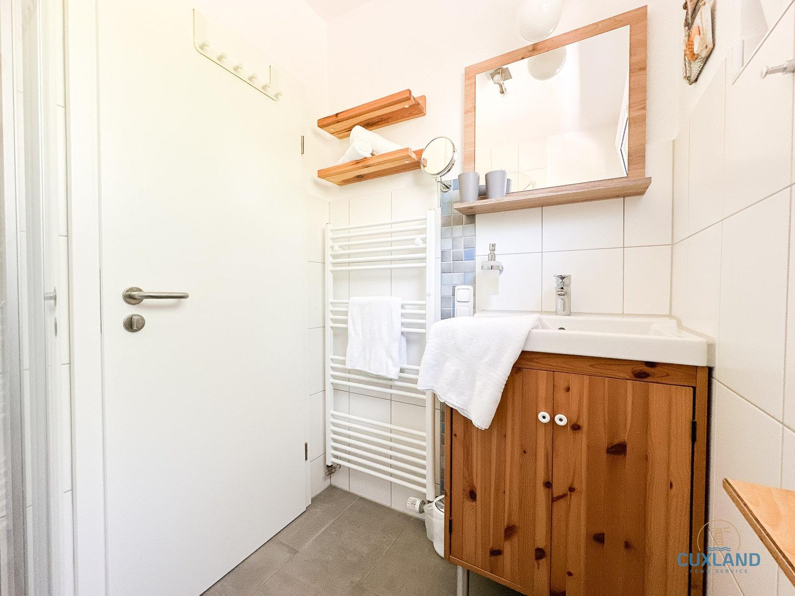 Badezimmer mit Holzwaschbecken, Spiegel und Handtuchhalter.