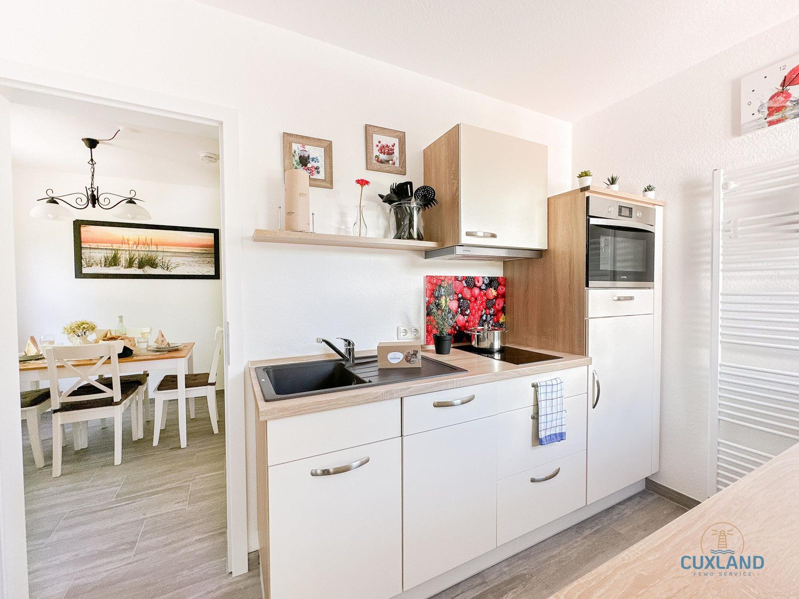 Küche mit weißen Schränken, Herd und Backofen. Essbereich mit Tisch und Stühlen sichtbar.