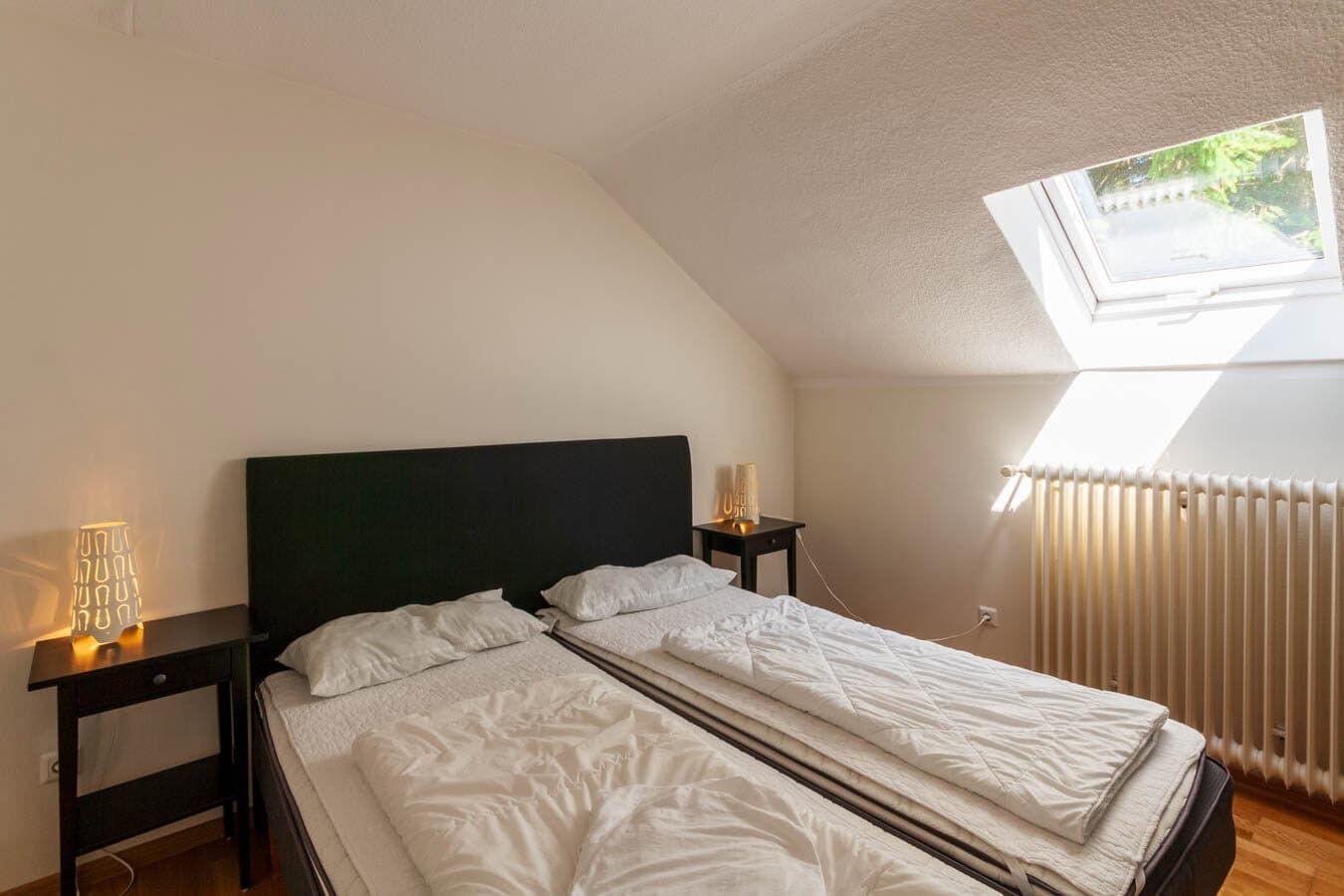 Schlafzimmer mit Doppelbett, zwei Nachttischen und Dachfenster.