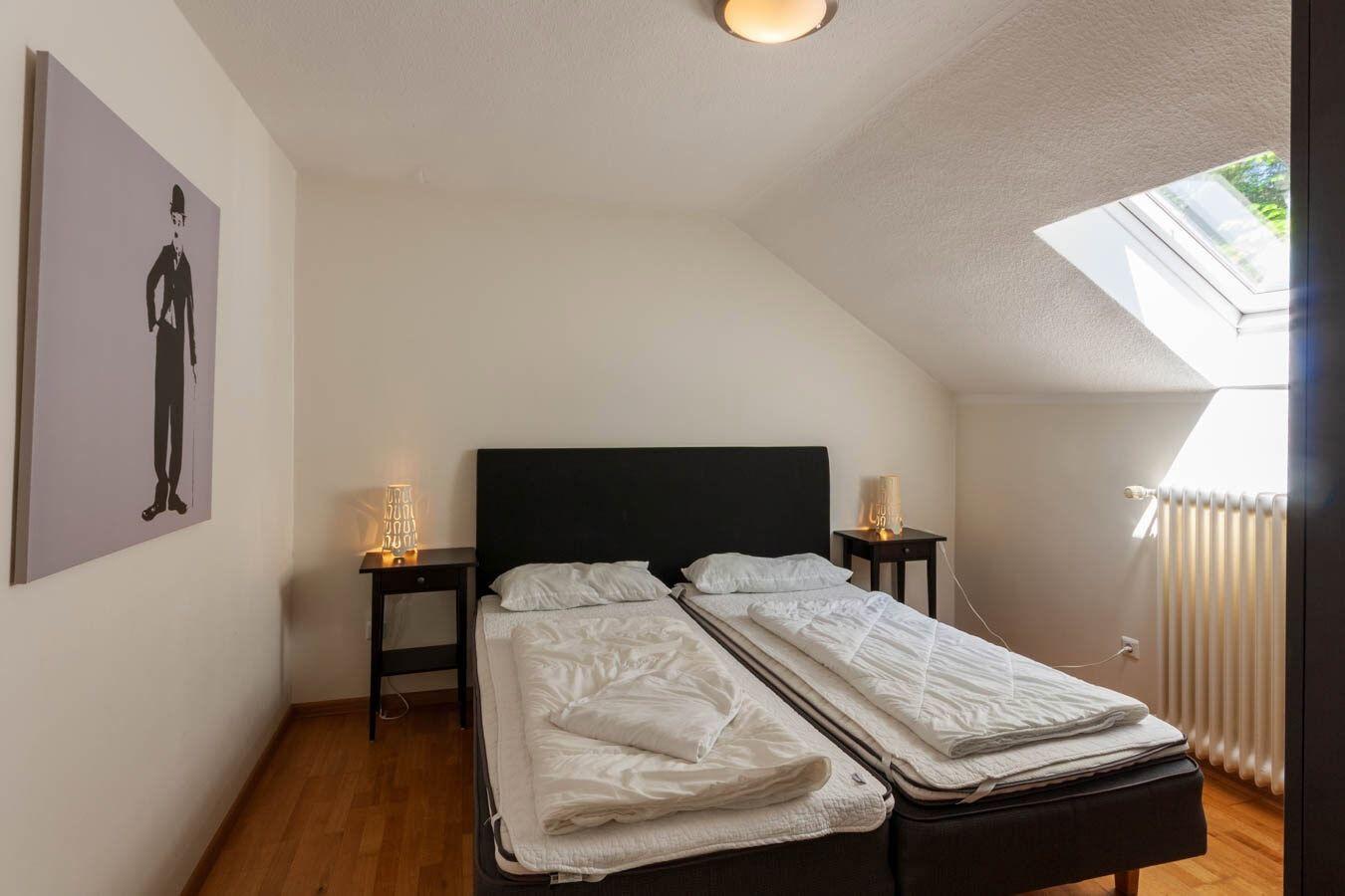 Schlafzimmer mit Dachschräge, zwei Matratzen und Fenster