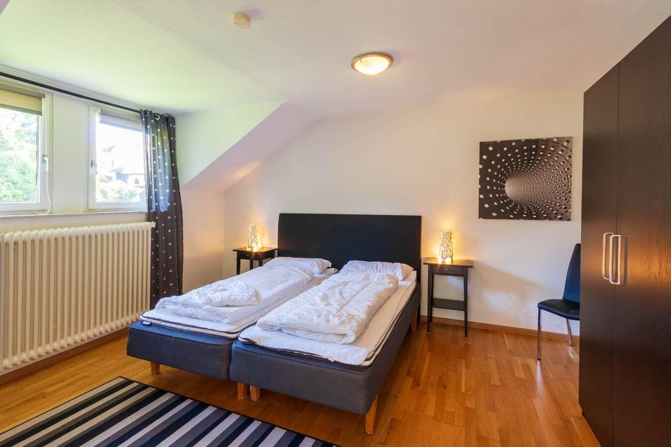 Zimmer mit Doppelbett, zwei Nachttischen, Schrank und Fenster mit Blick.