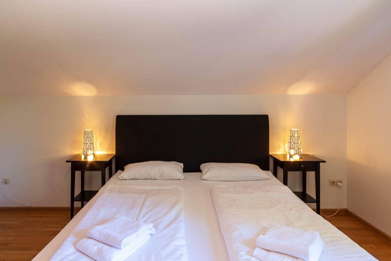 Schlafzimmer mit Doppelbett, zwei Nachttischen und Beleuchtung.
