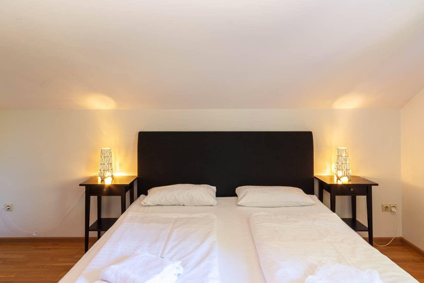 Schlafzimmer mit Doppelbett, zwei Nachttischen und Lampen an den Wänden.