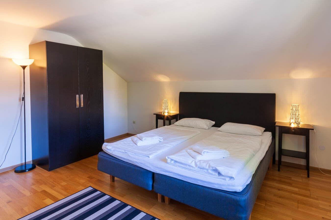 Schlafzimmer mit Doppelbett, zwei Nachttischen und einem Kleiderschrank.