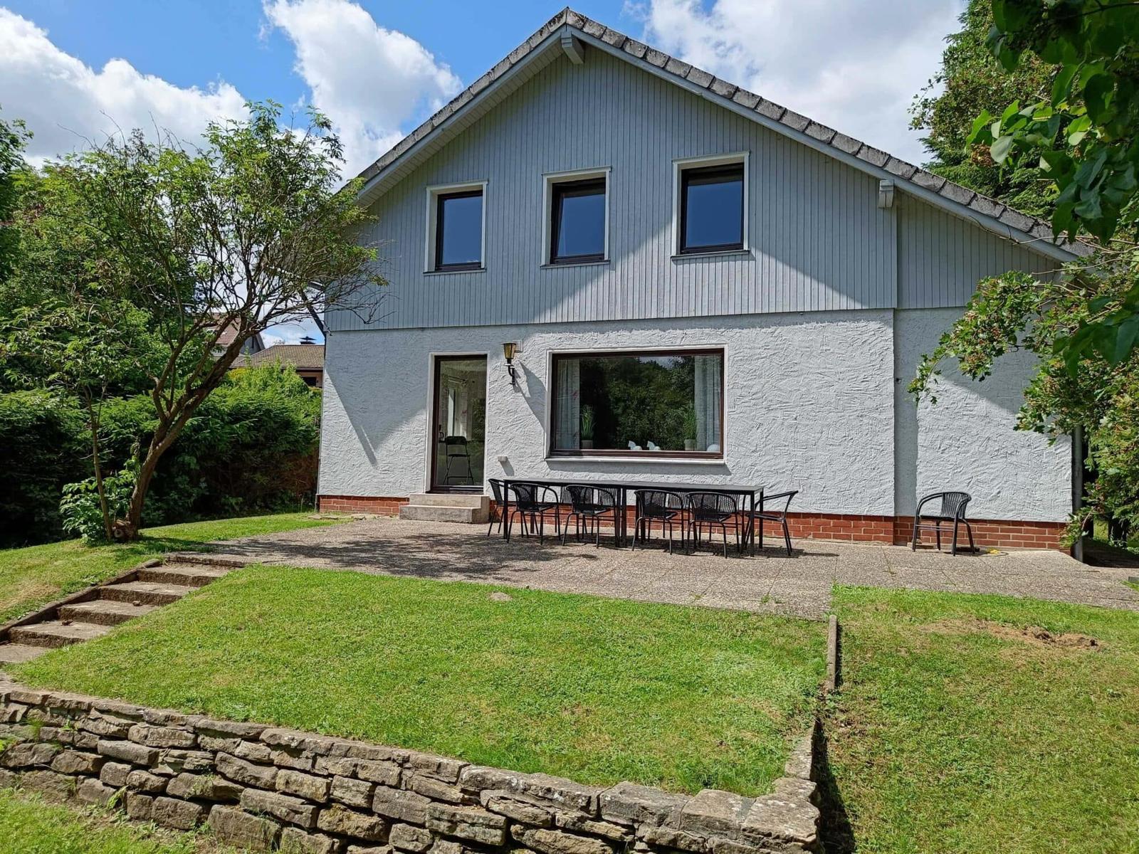 Haus mit Terrasse, Garten und Sitzgelegenheiten. Modernes Design mit Holz- und Putzfassade.