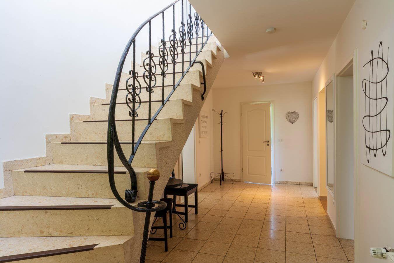 Haus mit geschwungener Treppe und Fliesenboden im Eingangsbereich.