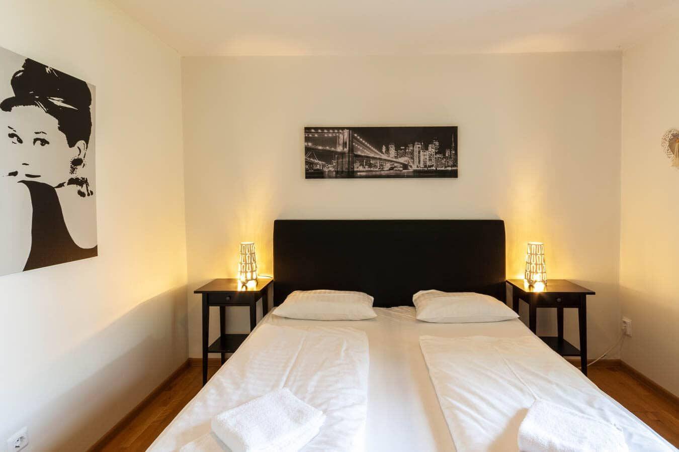 Schlafzimmer mit Doppelbett, zwei Nachttischen und Wandbildern.