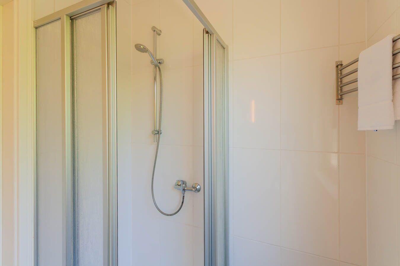 Dusche mit Glaswand und Handbrause an der Wand