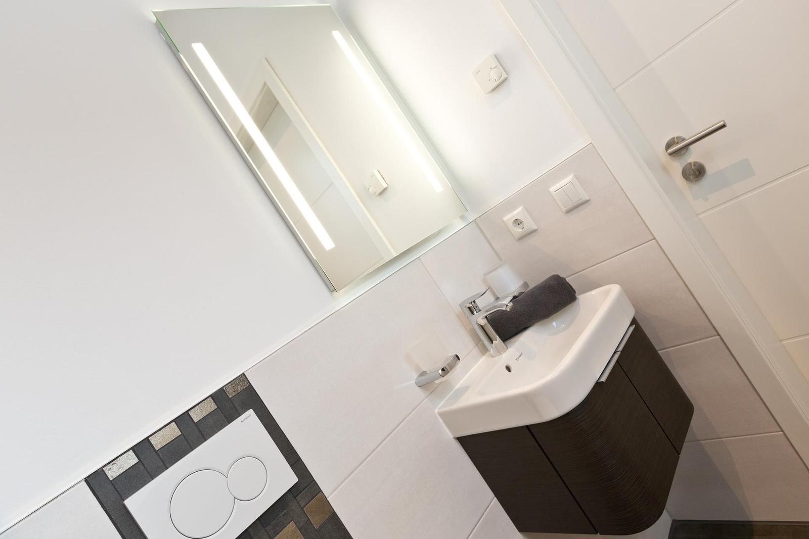 Badezimmer mit Waschbecken, Spiegel und Toilette