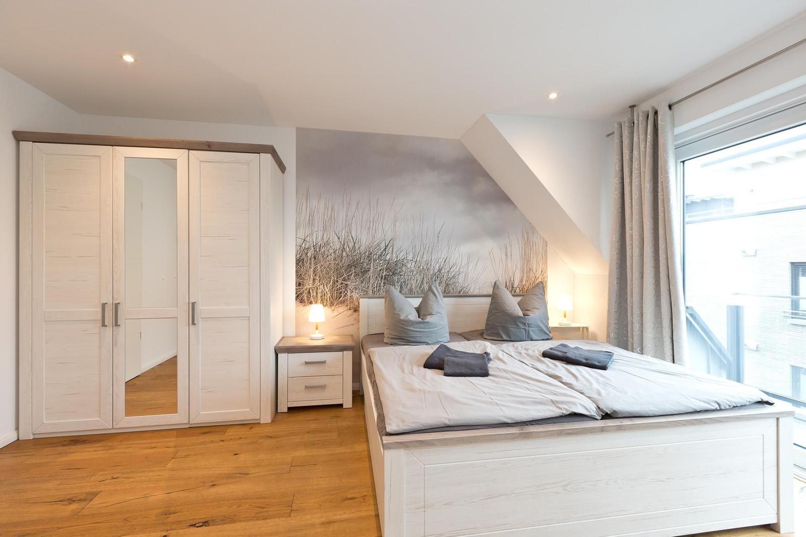 Schlafzimmer mit Doppelbett, Kleiderschrank und Fenster mit Blick.