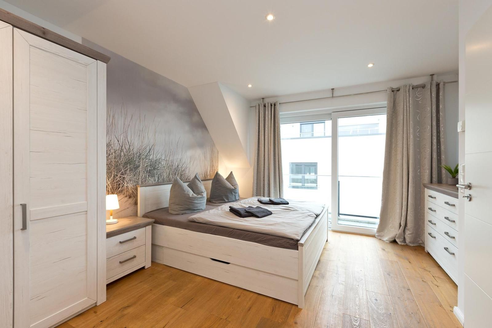 Schlafzimmer mit Bett, Schrank und Fenster zur Aussicht.