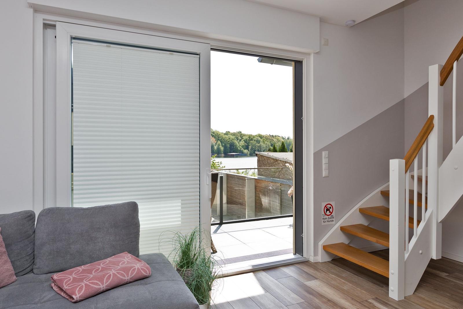 Wohnbereich mit Blick auf den See, Terrasse und Treppe.