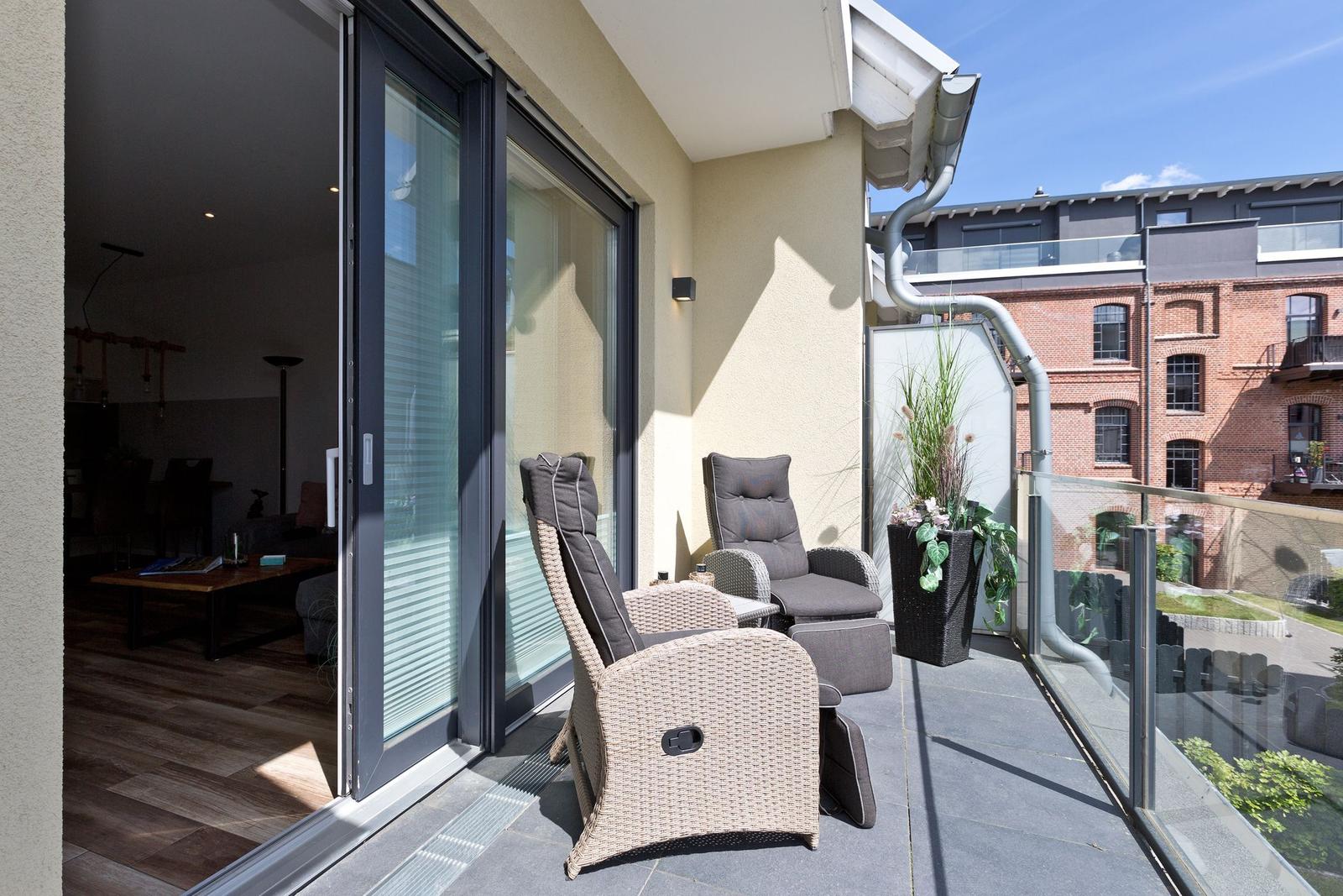 Terrasse mit zwei Liegestühlen und Blick auf Backsteinhaus