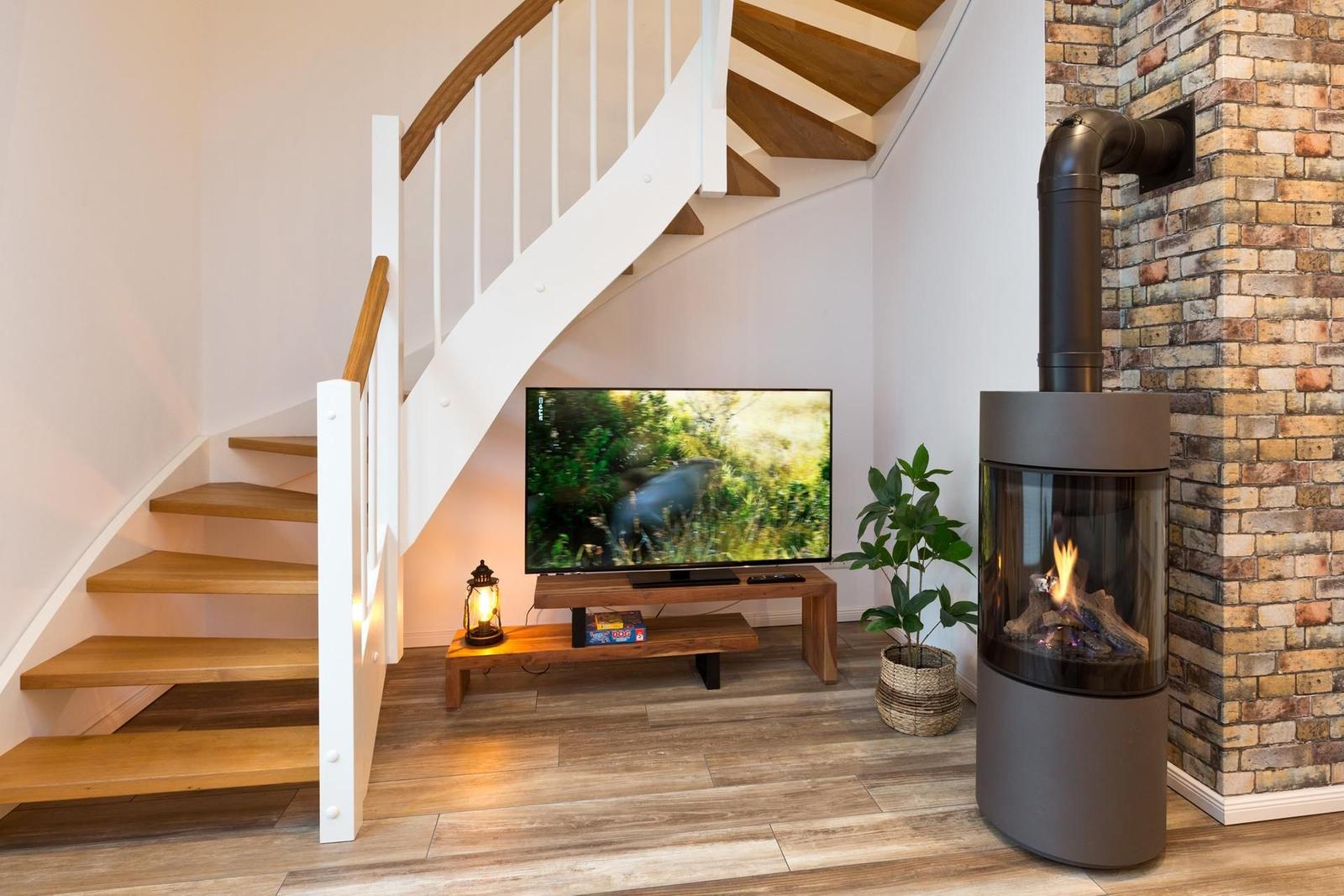 Treppenhaus mit Fernseher und Kaminofen an Backsteinwand