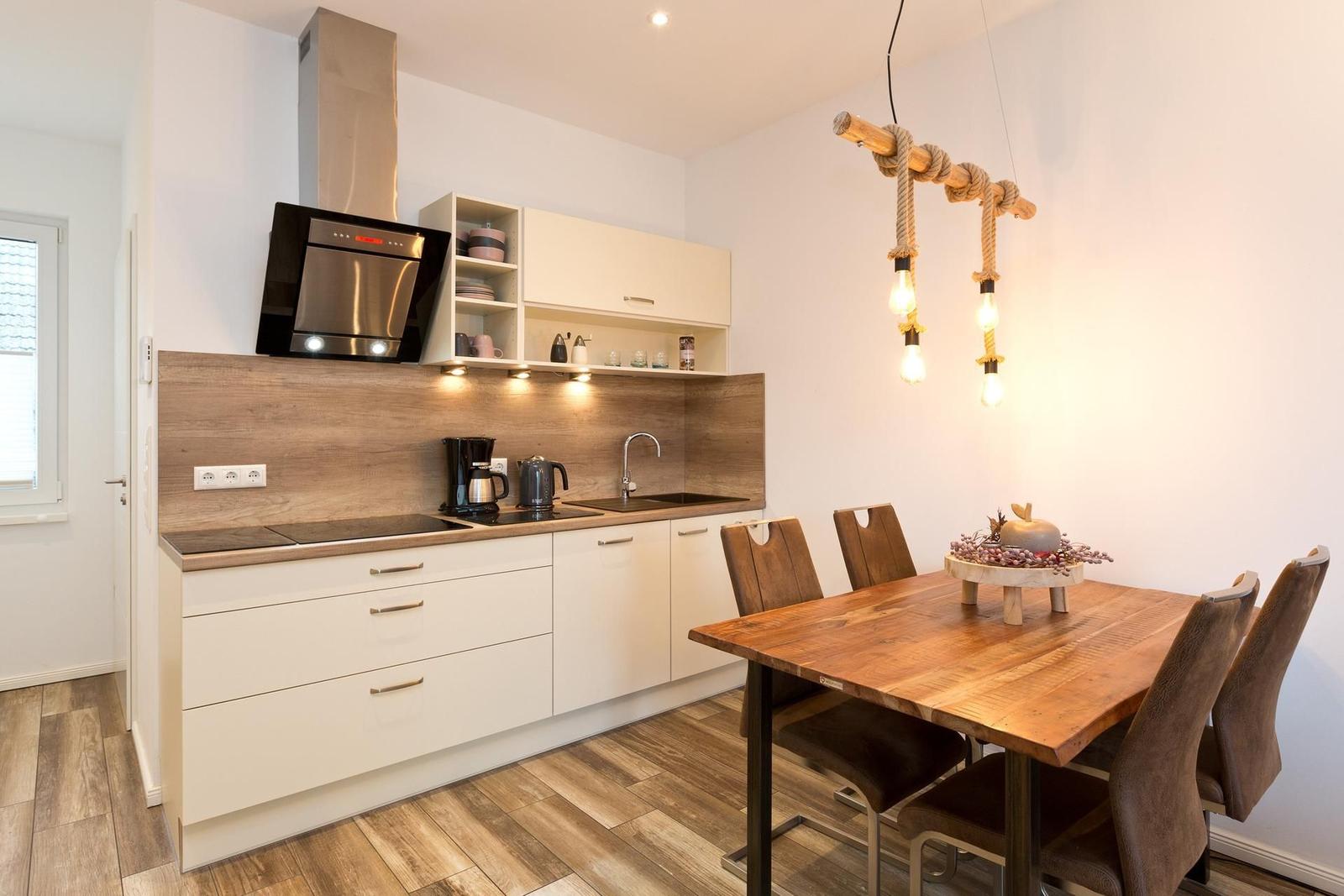 Küche mit Essbereich, Holztisch, Stühle und Holzoptik an der Wand.