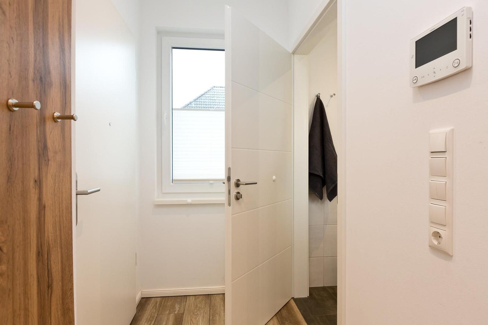 Haus mit Eingangsbereich, Tür, Fenster und Thermostat an der Wand.