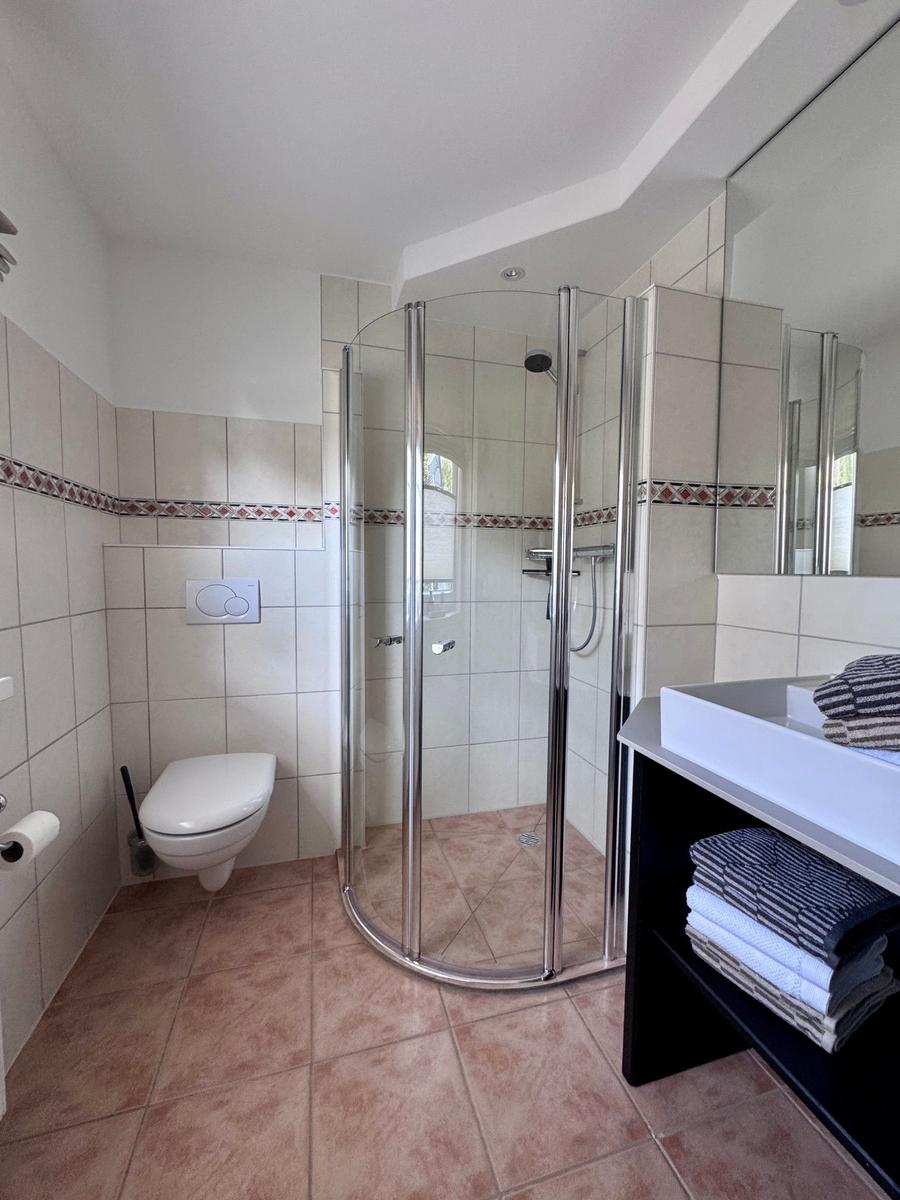Badezimmer mit Dusche, Toilette und Waschtisch mit Handtüchern.