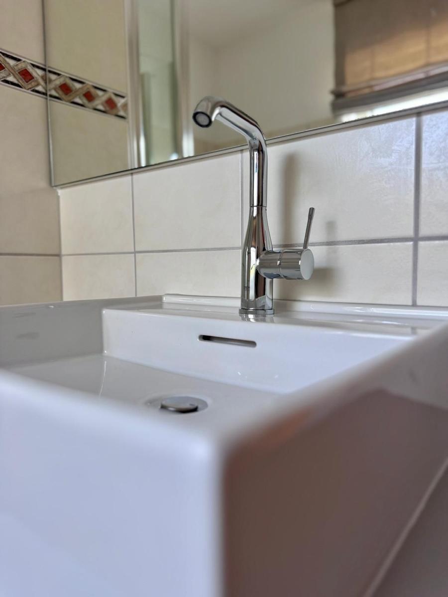 Weiße Waschbecken mit modernem Wasserhahn und Spiegel im Badezimmer.