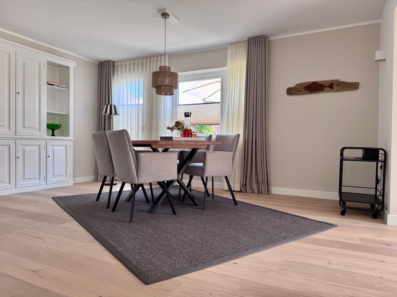 Esszimmer mit Tisch, Stühlen und Fenster. Wanddekoration und Schrank sind sichtbar.