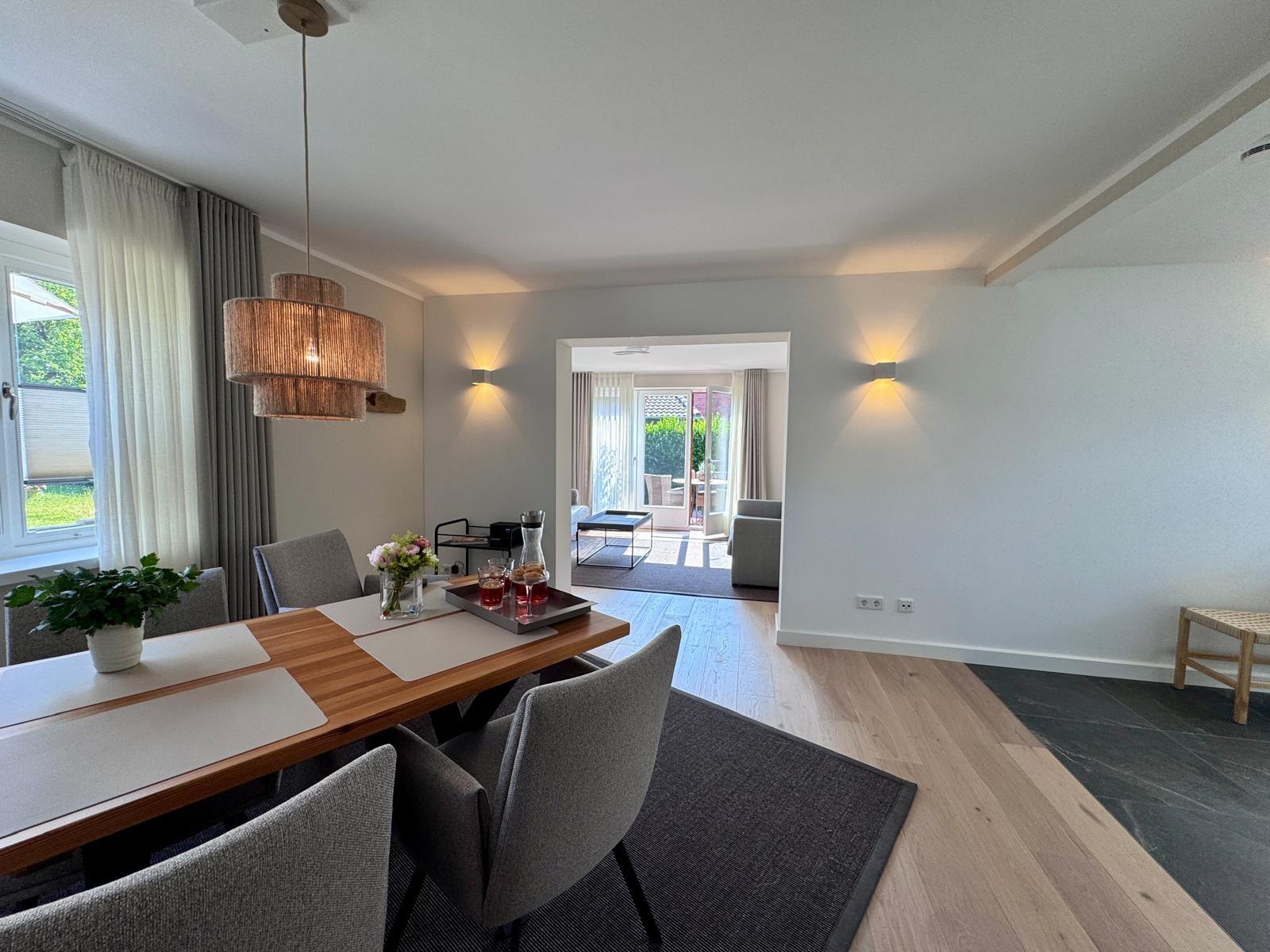Essbereich mit Tisch und Stühlen, Blick in Wohnzimmer mit Balkon.