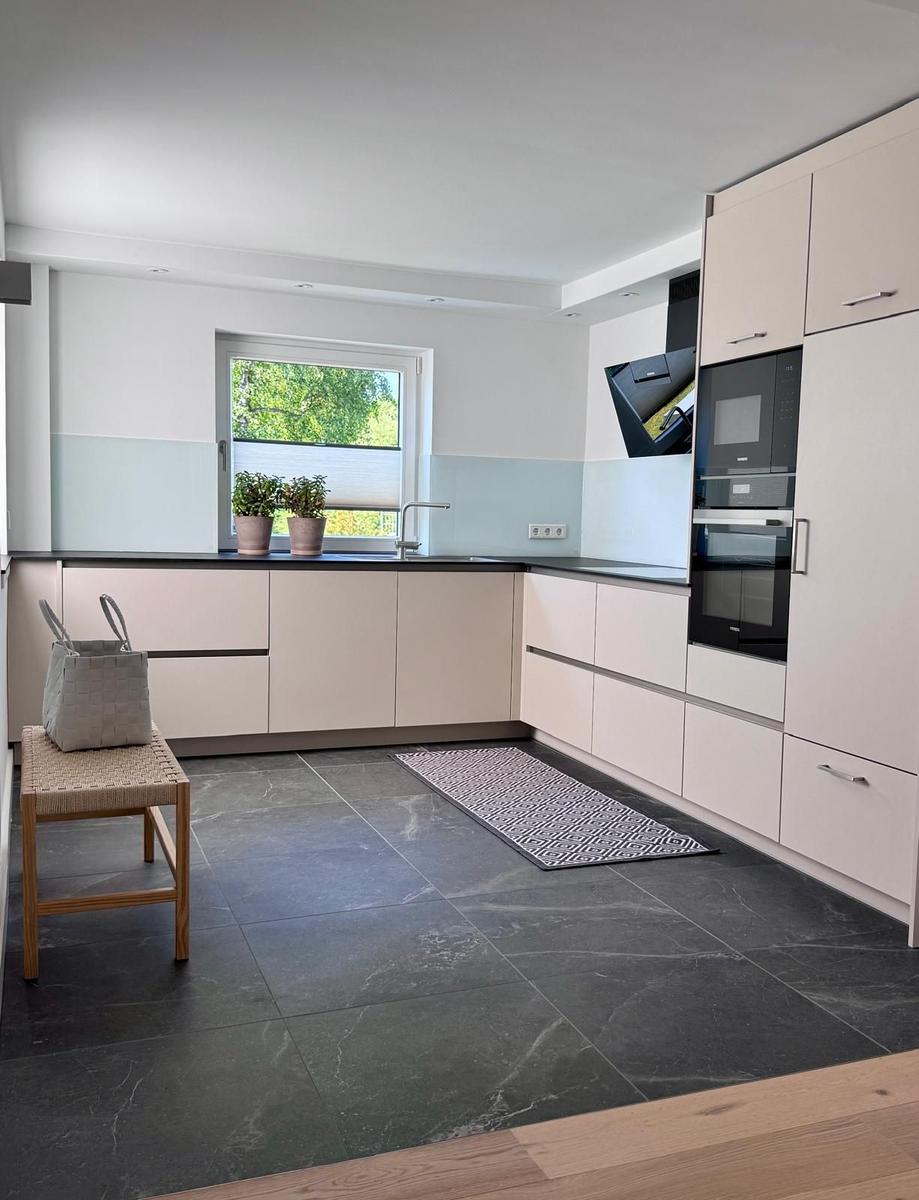 Moderne Küche mit integrierten Geräten und dunklem Bodenbelag.