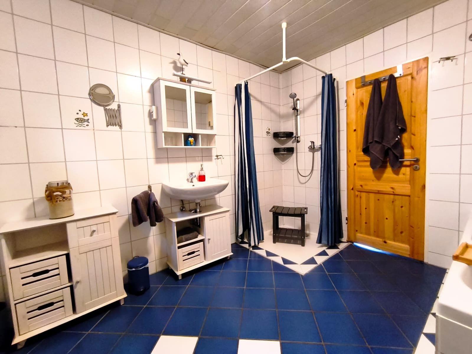 Das große Bad bietet Ihnen eine Dusche  und eine Badewanne. Ein stabiler und breiter Duschhocker steht bereit. Die Dusche ist ebenerdig.